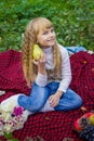 Beautiful little young baby in a pink hat with pear in hand. Beautiful child sitting on a red plaid.