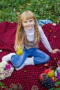 Beautiful little young baby in a pink hat with pear in hand. Beautiful child sitting on a red plaid.