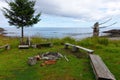 A beautiful location for a fire surrounded with benches, in a remote location with the ocean and shore in the background