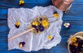 Beautiful lollipop caramel with edible violet flowers on parchment paper over on dark blue background. Flat lay. Top view.