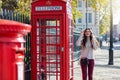 London traveler woman stands next to a red telephone booth and talking to her phone Royalty Free Stock Photo