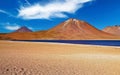 Beautiful lonely barren desert landscape in andes mountains highlands , dry sand area, dark blue lake, red volcano Miniques - Royalty Free Stock Photo