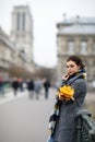 Beautiful lonely brunette girl in Paris, standing alone in a gray coat