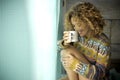 Beautiful lonely caucasian woman with curly hair and smile white enjoy her loneliness drinking a tea or coffee at home in front of