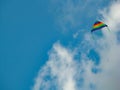 A beautiful and lonely colorful kite in blue, green, yellow, red colors soaring in the air on a beautiful blue sky day with few Royalty Free Stock Photo