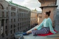 Beautiful lonely girl sitting on the roof in the old town of dreams