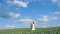 A beautiful lonely girl stands in the middle of a green field with her arms outstretched Royalty Free Stock Photo