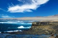 Beautiful lonely wild rough south-east coast, jagged rocks, strong waves, dry arid sand dunes, steep cliffs, clear blue sky -