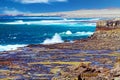 Beautiful lonely wild rough south-east coast, jagged rocks, strong waves, dry arid sand dunes, steep cliffs, clear blue sky -