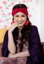 A beautiful long black hair lady with a red turban and purple blanket is sitting and smile with elegant gesture on a big dark Royalty Free Stock Photo