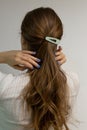 Beautiful long blond natural hair with flower hair clip snap view from the back against white background. Caucasian woman with Royalty Free Stock Photo