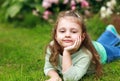 Beautiful long curly hair kid girl lying on green grass in fashi Royalty Free Stock Photo