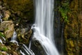 Beautiful long exposure photo of a waterfall rushing down a cliff and bursting onto a steep rocky mountainside Royalty Free Stock Photo