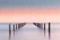 Beautiful long exposure shot of pilings jutting out of the calm waters. AI-generated.