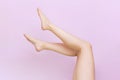 Beautiful long female legs with smooth skin after depilation on a pastel pink background. Royalty Free Stock Photo