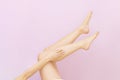 Beautiful long female legs with smooth skin after depilation on a pastel pink background. Royalty Free Stock Photo