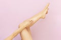 Beautiful long female legs with smooth skin after depilation on a pastel pink background. Royalty Free Stock Photo