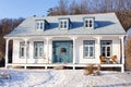 Beautiful long french-style ancestral white clapboard house with blue trimmed windows, blue door and metal roof Royalty Free Stock Photo