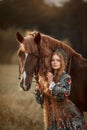 Beautiful young woman in national russian style with red draft horse