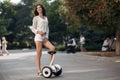 Beautiful long-haired brunette in a green park outdoors riding a segway Royalty Free Stock Photo