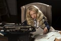 Beautiful long haired curly blonde schoolgirl tiredly learns homework in a classic vintage interior room, sitting at a table Royalty Free Stock Photo