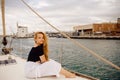 A beautiful long-haired girl sits on the bow of a barred yacht and enjoys life. The blonde is resting in the open sea or ocean Royalty Free Stock Photo