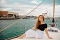 A beautiful long-haired girl sits on the bow of a barred yacht and enjoys life. The blonde is resting in the open sea or ocean Royalty Free Stock Photo