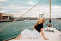 A beautiful long-haired girl sits on the bow of a barred yacht and enjoys life. The blonde is resting in the open sea or ocean Royalty Free Stock Photo