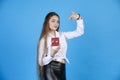 Beautiful long-haired lady in shirt pointing at wee red decorated gift box, while looking at camera. Royalty Free Stock Photo