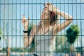 Beautiful long haired lady standing with her eyes closed and leaning on the fence Royalty Free Stock Photo