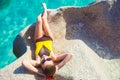 Beautiful long haired woman in onepiece swimsuit relaxing on the rocks over the sea. Mahe Island, Seychelles