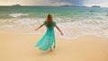 Woman walks to the stormy cloudy ocean on sand beach. Girl in blue swimsuit dress tunic. Concept rest in sea, tropical Royalty Free Stock Photo