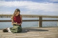 Beautiful long haired woman writing in journal near rural lake.