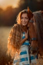 Beautiful young woman with red tinker horse in oats field