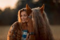 Beautiful young woman with red tinker horse in oats field