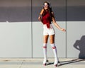 Beautiful long-legged asian girl skating in roller skates and enjoying an ice cream on a summer day Royalty Free Stock Photo