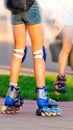 Beautiful long-legged girl posing on a vintage roller skates in denim shorts and white T-shirt in the skate park on a Royalty Free Stock Photo