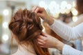 Beautiful, with long, red-haired hairy girl, hairdresser weaves a French braid Royalty Free Stock Photo