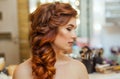 Beautiful, with long, red-haired hairy girl, hairdresser weaves a French braid, in a beauty salon. Royalty Free Stock Photo