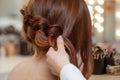 Beautiful, with long, red-haired hairy girl, hairdresser weaves a French braid, close-up in a beauty salon. Royalty Free Stock Photo