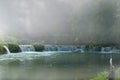 Beautiful waterfall on small cliff with thick fog in the park