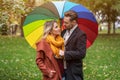 Beautiful in love couple standing in the park under a rainbow colored umbrella looking at each others eyes. A beautiful Royalty Free Stock Photo