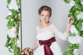 Beautiful lovely bride is sitting on a swing with a beautiful bouquet of colorful flowers in a white dress with evening hairstyle Royalty Free Stock Photo