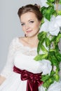 Beautiful lovely bride is sitting on a swing with a beautiful bouquet of colorful flowers in a white dress with evening hairstyle Royalty Free Stock Photo