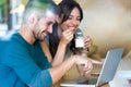 Beautiful lovely young couple using their laptop and having breakfast in the kitchen at home. Royalty Free Stock Photo