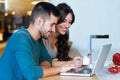 Beautiful lovely young couple using their laptop and having breakfast in the kitchen at home. Royalty Free Stock Photo