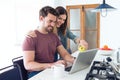 Beautiful lovely young couple using their laptop and having breakfast in the kitchen at home Royalty Free Stock Photo