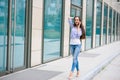 Beautiful lovely young woman with long brunette hair wearing dress walking outdoors, talking on mobile phone Royalty Free Stock Photo