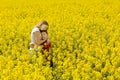 Beautiful loving teenage girl and young brother together in sweet hug, surrounded by a meadow filled with yellow flowers.