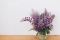 Beautiful lupine bouquet on wooden table in white room. Gathering wildflowers. Purple lupine flowers Royalty Free Stock Photo